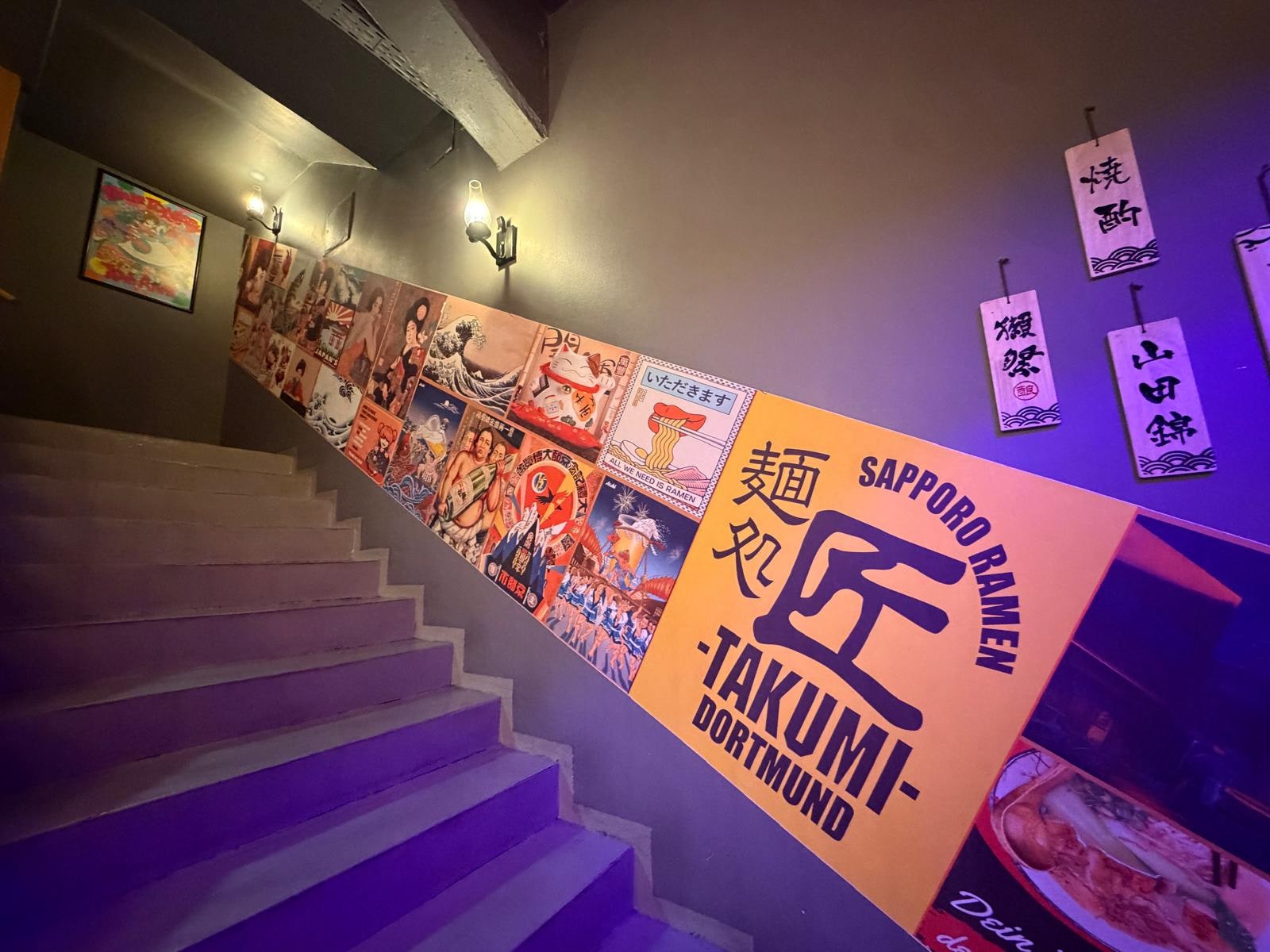 Wandgestaltung mit Takumi-Dortmund-Branding an der Treppe im Restaurant